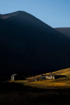 A wooden house on a hill in the altai at the foot of the high mountains.