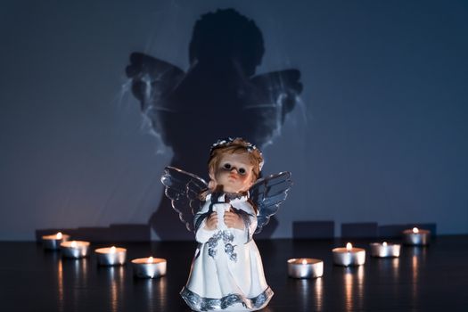 White Christmas angel with lighted candles in the Church. Spiritual deity in religion.