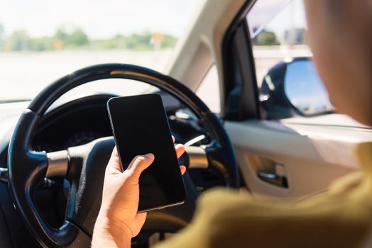 Asian woman inside a car and using a hand holding mobile smartphone blank screen while driving the car in the morning during going to work on highway, Transportation and vehicle concept