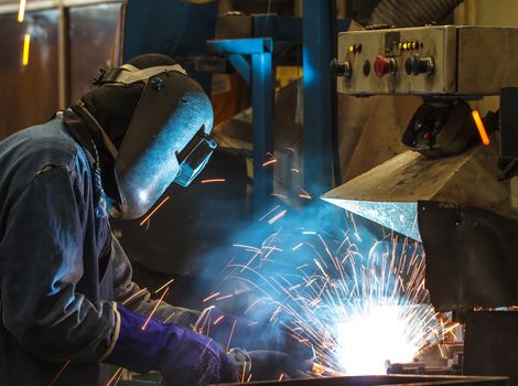 worker with protective mask welding metal