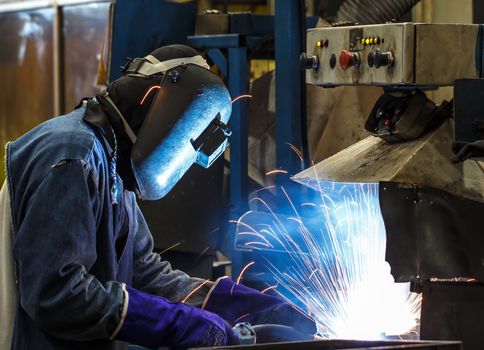 worker with protective mask welding metal