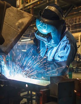 worker with protective mask welding metal