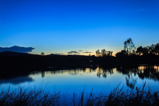 last bright sunrays above the lake late at cloudy evening