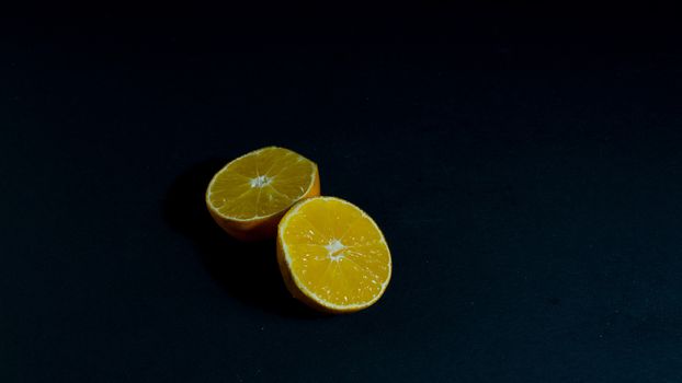 Yellow-orange tangerine clementine on black background.