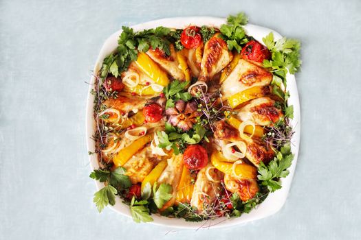 Fried breast and chicken drumsticks with vegetables and cherry tomatoes on a white plate