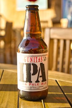 Big Sur, United States, November 2013: Illustrative Editorial: Lagunitas IPA India Pale Ale beer bottle against strong sunlight. Wooden table.