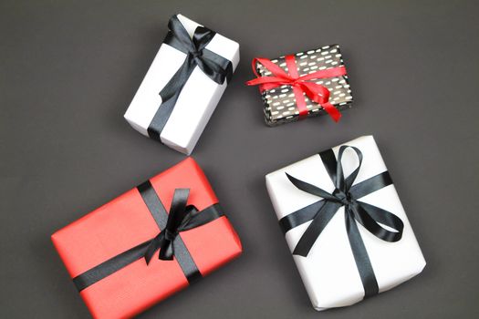 Gifts wrapped with colorful paper and red and black bows on black background