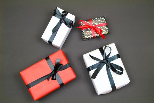 Gifts wrapped with colorful paper and red and black bows on black background