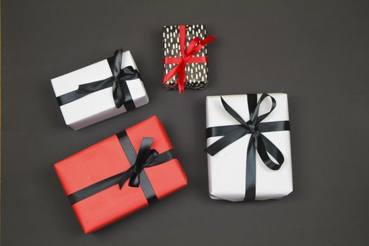 Gifts wrapped with colorful paper and red and black bows on black background