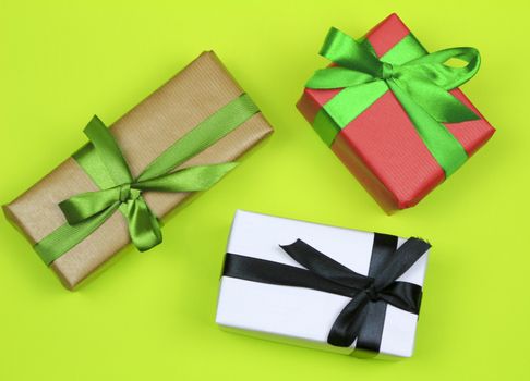 Gifts wrapped with colorful paper and green and black bows on green background