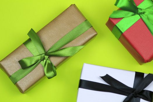 Gifts wrapped with colorful paper and green and black bows on green background