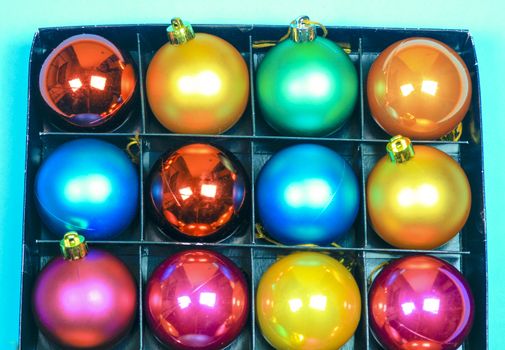 Box of multicolor Christmas balls on green background