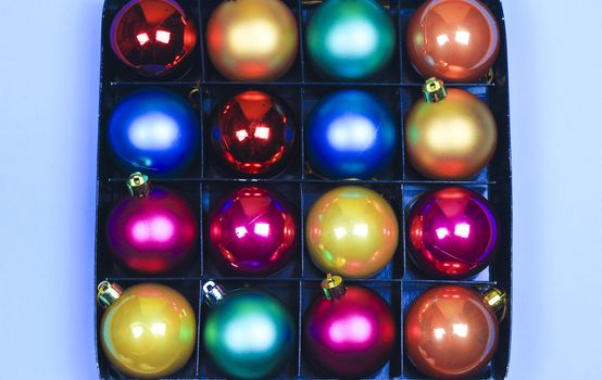 Box of multicolor Christmas balls on blue background