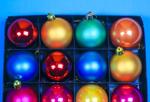 Box of multicolor Christmas balls on blue background