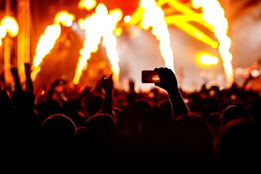 Silhouette of hands using camera phone to take pictures and videos at live concert.