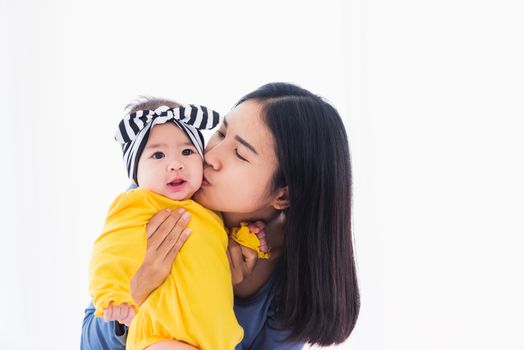 Portrait of beautiful young Asian mother kissing her infant newborn baby in a white bed, The mom loves his child, Healthcare and medical and mother day concept