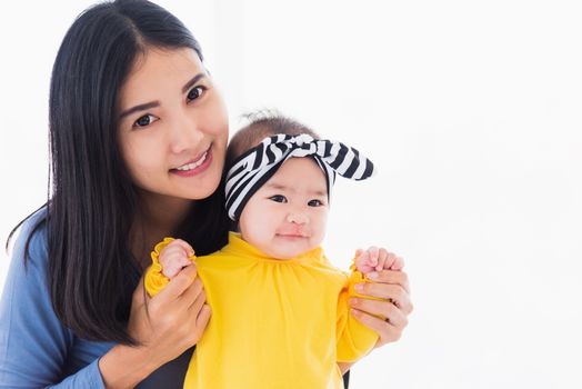 Portrait of beautiful young Asian mother playing and smiling together with his newborn little baby at home, Parent mom and little kid relaxing in the bedroom, Family having fun together