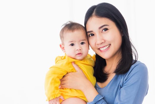 Portrait of beautiful young Asian mother holding his newborn little baby in her arms at home, Parent mom hugging her newborn child, happy family