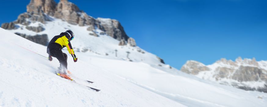 Alpine mountain skier skiing downhill in high mountains Alps Dolomites region of Northern Italy ski resort piste
