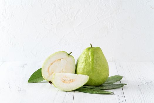 Delicious beautiful guava set with fresh leaves isolated on bright white wooden table background, close up.