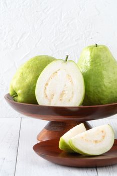 Delicious beautiful guava set with fresh leaves isolated on bright white wooden table background, close up.