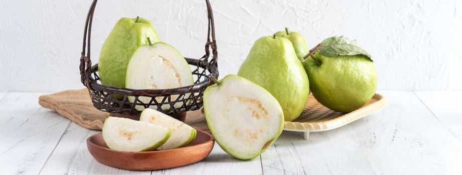 Delicious beautiful guava set with fresh leaves isolated on bright white wooden table background, close up.