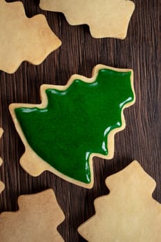 Top view of decorated green plain flavor gingerbread Christmas tree cookie on wooden table background with copy space, concept of holiday celebration.