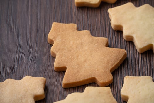 Top view of decorated green plain flavor gingerbread Christmas tree cookie on wooden table background with copy space, concept of holiday celebration.