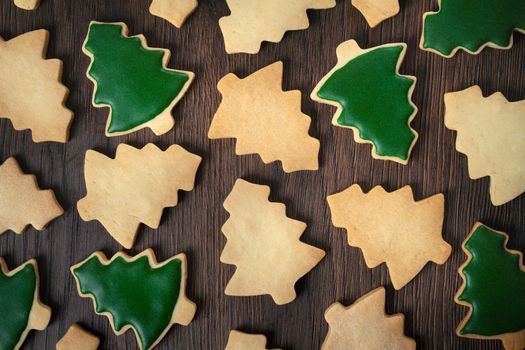 Top view of decorated green plain flavor gingerbread Christmas tree cookie on wooden table background with copy space, concept of holiday celebration.