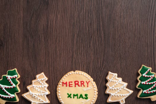 Top view of decorated green plain flavor gingerbread Christmas tree cookie on wooden table background with copy space, concept of holiday celebration.