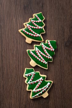 Top view of decorated green plain flavor gingerbread Christmas tree cookie on wooden table background with copy space, concept of holiday celebration.