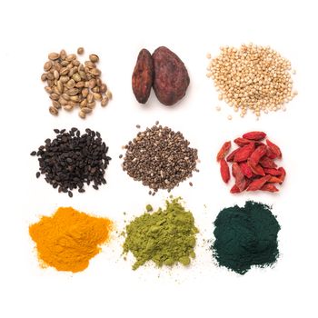 Small heap of various superfoods on white background.Superfood as chia,spirulina,matcha tea powder,raw cocoa bean,goji berry,hemp,quinoa,black sesame,turmeric.Top view.Isolated on white,clipping path