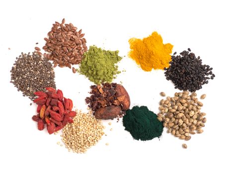 Small heap of various superfoods on white background.Superfood as chia,spirulina,matcha tea,raw cocoa bean,goji,hemp,quinoa,black sesame,turmeric,flax seed.Top view.Isolated on white,clipping path
