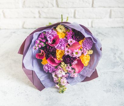 Lilac bouquet with arum lily or calla, roses, dianthus, chrysanthemum, limonium, matthiola. Focus on calla. Shallow DOF, copy space