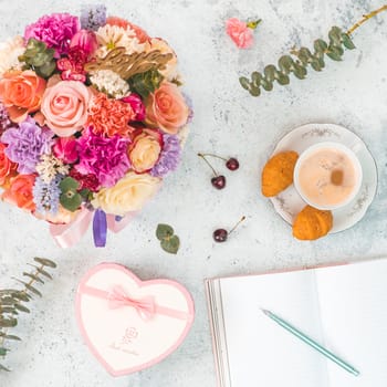 Flat lay with beautiful bouquet, coffee cup, gift box in heart shape, empty notebook for writing dreams and ideas. Top view. Square format. Concept and idea image for social media.
