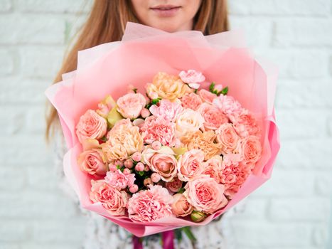 Beautiful bouquet with differen tpink flowers in woman hands. Nice subtle delicate pink bouquet with roses, dianthus, hypericum, clove. Shallow DOF
