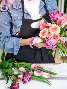 Florist hands collect bouquet of flowers in studio. Florist creating order, making rose, peony and tulip bouquet in flower shop. Florist are doing bouquet. Florist at work.Vertical.Copy space for text