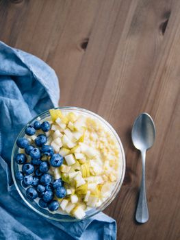 Top view of bowl with millet porridge on wooden table background. Organic millet porridge with blueberry and pear, copy space for text. Soft focus, shallow DOF. Vertical