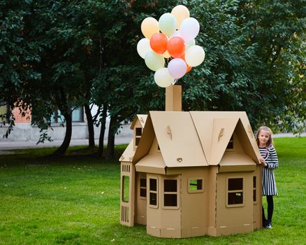 Child playing in a cardboard playhouse. Eco concept.