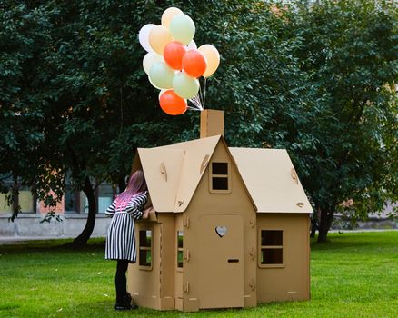 Child playing in a cardboard playhouse. Eco concept.