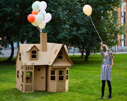 Child playing in a cardboard playhouse. Eco concept.