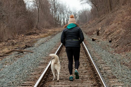 Hamilton Ontario, March 24 2020: Editorial photo of a women walking on train tracks with her dog. Editorial theme of loneliness . High quality photo