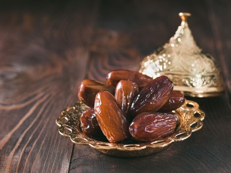 Metal plate of dates on dark wooden table. Dried dates with copy space.
