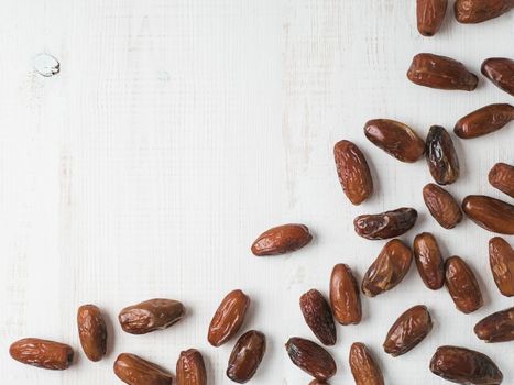 Sweet dried dates on white wooden background. Dried dates with copy space. Sugar free alternatives concept. One edge image with space for text. Top view or flat-lay.