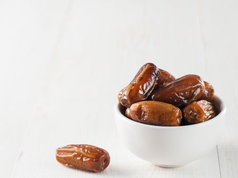 Small bowl of sweet dried dates on white wooden table. Organic dried dates with copy space.