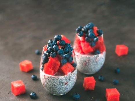 Healthy breakfast concept and idea - chia pudding with watermelon and blueberries. Two glass with chia pudding dressed watermelon and blueberry on dark background. Copy space for text.