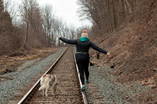 Hamilton Ontario, March 24 2020: Editorial photo of a women walking on train tracks with her dog. Editorial theme of loneliness . High quality photo