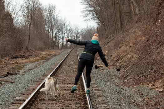 Hamilton Ontario, March 24 2020: Editorial photo of a women walking on train tracks with her dog. Editorial theme of loneliness . High quality photo