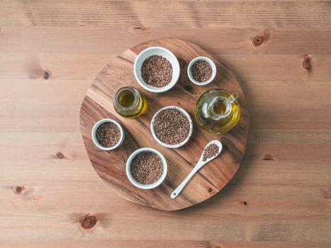 flax seeds and flaxseed oil on wooden table. Set of small bowls with organic flax seed or linen seed. Flax oil is rich in omega-3 fatty acid. Copy space. Top view or flat-lay.