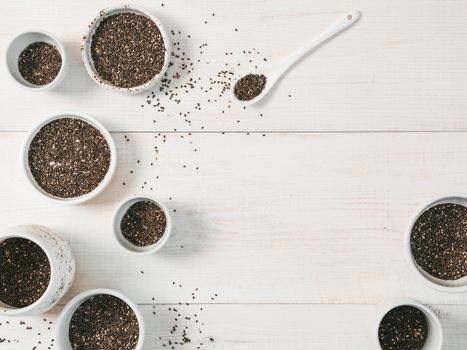 Organic chia seeds on white wooden table. Set of small bowls with organic chia seed. Superfood concept. Copy space. Top view or flat-lay.